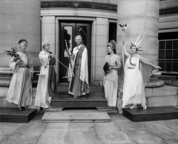 Five women in costume during rehearsal for the Americanization pageant, called "A Thoroughfare for Freedom," which will take place on the balcony and steps of the Monona Avenue entrance of the Wisconsin State Capitol. Left to right: Elsie Swarner, representing Peace; Mary Hanley, Justice; Mary Rennebohm, America; Mrs. John Cole, Righteousness; and Grace Livesey, Liberty.