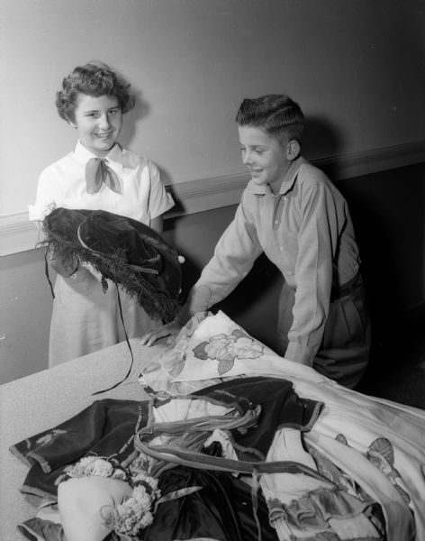 School children Nancy and Billy Hoppe look at costumes to be worn by actresses in the upcoming Americanization Pageant.