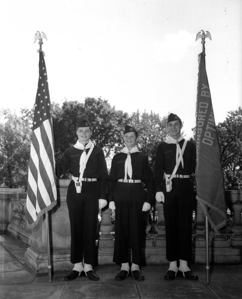 Outdoor group portrait of a Boy Scouts color guard that participated in the Americanization Pageant. They are, from left: David Ross, David Langhammer, and John Lee.
