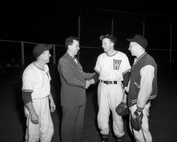 League Commissioner C.A. Lewis congratulates Manager Erhardt Toppe of Wyocena's baseball team after winning the Home Talent League's championship in Rio, Wisconsin.  Left to right: Patsy Pease, catcher; Lewis; Toppe; and Bob Spear, pitcher.