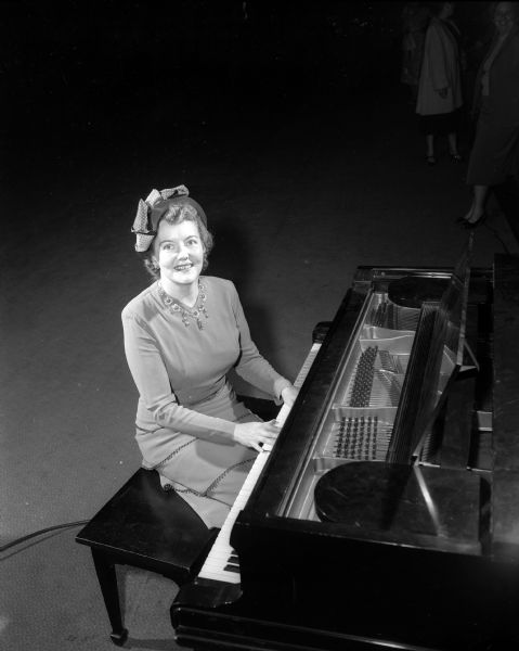 Vera Weikel Adams, a lyrico-spinto soprano, sits at a piano during the Zonta Style Show. Adams sang two groups of songs during the show.