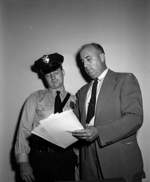 Rookie police officer Thomas McCarthy stands beside Police Inspector Philip Onkey. McCarthy is one of thirteen recruits receiving training in the Madison Police Department's 1953 training program.