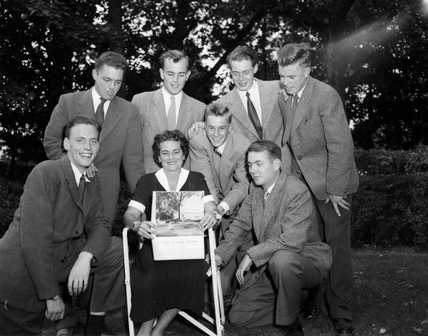Seven students from Sweden, Denmark, and Norway and Margaret Brittingham, wife of Thomas Brittingham, Jr. posing for a portrait outdoors. The students are attending the University of Wisconsin for a year and living the life of a university fraternity man. Thomas Brittingham started the Brittingham Scholars Viking Program in 1952 to bring Scandinavian students to the University of Wisconsin. They are looking at the "Life Magazine" article of September 6, 1948, which describes the good life in Madison. Thomas Brittingham Jr. died April 16, 1960. The Brittingham Scholars program, founded in 1952 continued through 1962.
