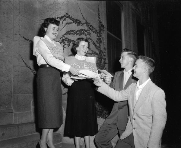 Two hostesses for the Memorial Union student orientation open house at the University of Wisconsin greeting two Milwaukee freshmen, Bob Henderson and Ernie Krubsack. The student hostesses are Judy Wiedenbeck, left, and Lois McCabe, both of Madison.