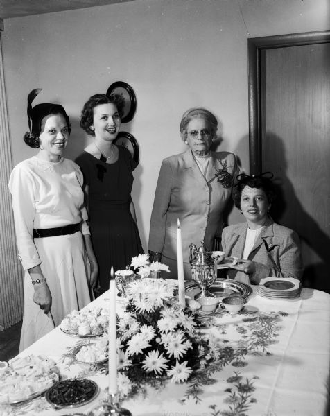 Portrait of four women at a tea for the Woman's Auxiliary of the Dane County Dental Society.  Standing at the tea table are, left to right: Alzada Mc Cormick, Edith Boyle and Evelyn Wheeler. Pouring tea is Marjorie C. Thielke.