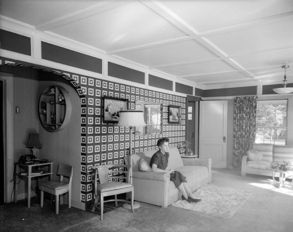 The living room of the Albert Herrington home, located at 3724 Tonyawatha Trail. Mrs. Herrington is sitting on a sofa.