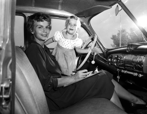 Mrs. Garth K. Voight and daughter Valerie Voight, 18 months, sit in the front seat of an automobile. Mrs. Voight is membership chairman for the Junior Division of the University League. The Junior Division is a support organization for UW faculty women and wives of faculty members.