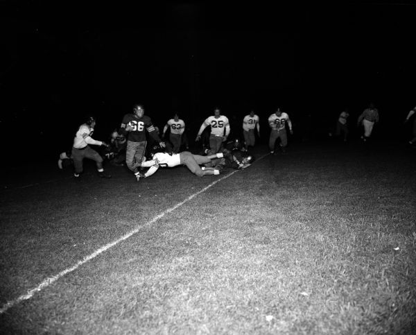 Action shot of East High School's Don Marks (#66) dodging a tackle thrown by Central High School's Louis Cassini (#20).