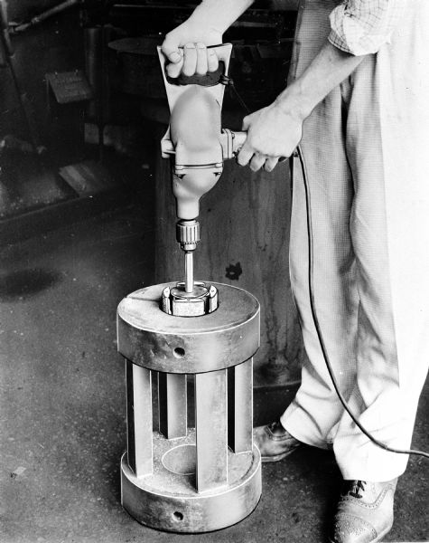 A man uses a Monarch Machine Company abrasive grinder.