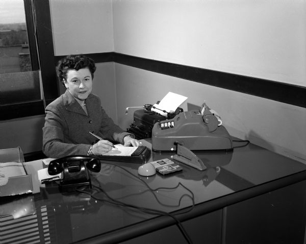 Seated at her desk is Lorraine C. Jones, secretary to T.F. Wisniewski, a director at the State Board of Health. She is portraying a "modern" secretary as an activity during National Business Women's Week which is being observed with special features in the press, radio, and television stations to show the progress which women have made through the years. The project is sponsored by the Madison Business Women's and Professional Women's organizations.