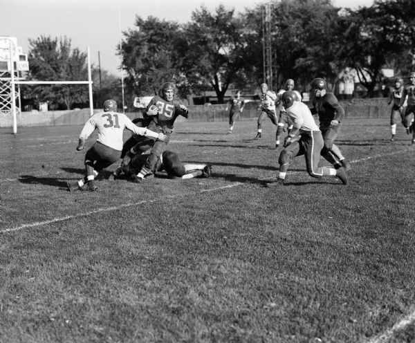 Action photograph of a semi-professional football game between the Wausau Muskies and Delavan Red Devils at Breese Stevens Field. Features Wausau's Quintin Kaisershot (#35) and Delavan's Gil Krueger (#31).