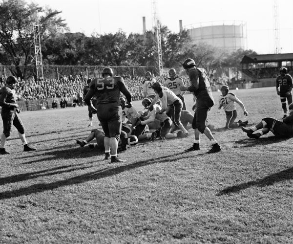Gene Evans (Wausau) makes a touchdown during a semi-professional football game between the Wausau Muskies and Delavan Red Devils at Breese Stevens Field. Also shown: Charlie Berndt of Wausau and Delavan players Louis Behling and Norm Rohter.