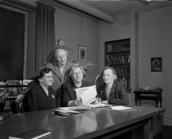 Officers of the Madison Council of United Church Women plan the program for World Community Day. Seated left to right are: Elva Jabas, a member of Pilgrim Congregational Church, treasurer; Jessie Briese, a member of the First Congregational Church, vice-president; Gladys Kneebone, a member of the South Shore Methodist Church, secretary. Standing is Pearl Jennings, a member of the Glenwood Moravian Church and president of the Council.