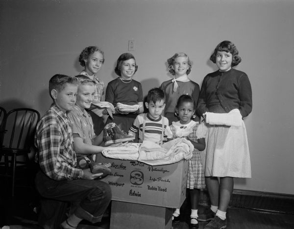 Sunday School children, mostly from the Pilgrim Congregational Church, pack gifts to be sent to refugee camps all over the world as part of World Community Day, held at Grace Episcopal Church. In the front (from left) are: Bill Macy, Bobby Wang, Zed Ostenso, and Patricia Styles. Standing are: Margaret Utter, Faye Long, Emily Huegel, and Linda Briggs.