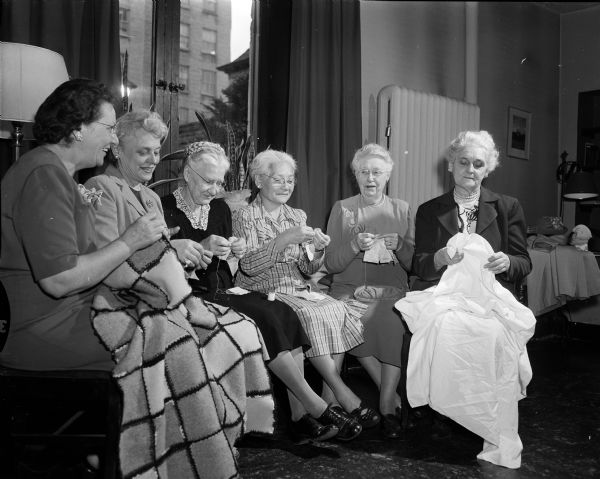 Six members of the social relations group of the Guild of the First Baptist Church work on  making blankets, curtains, bed linens, and other needed articles for Christian centers for the world's refugees. From left to right are: Edith Henney, Maude Shoemaker, Rena Gigous, Lun Fong Lem, Mary Gillin, and Florence Linden.