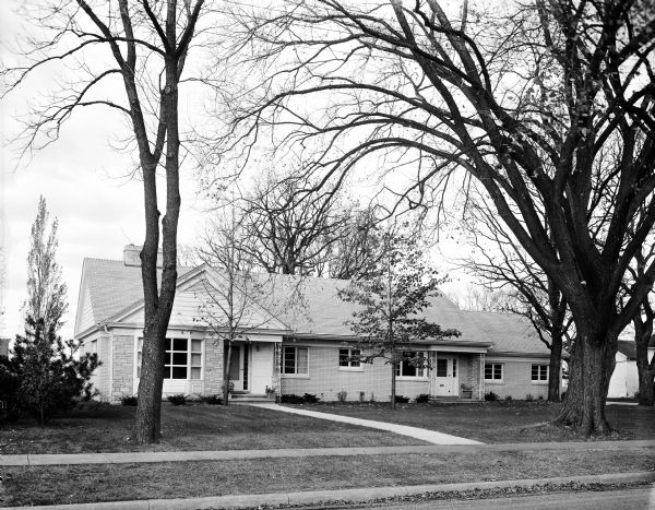 Exterior view of the newly-built Leo Scheberle house located on the edge of town. The house is constructed in the Mid-Century style and clad in cream-colored brick and lannon stone.