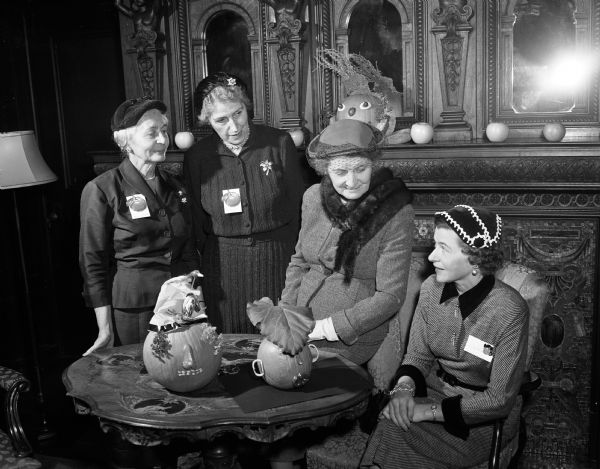 The American Association of University Women (AAUW) honors teachers at a dessert party at the College Club. Pictured from left to right are three of the teachers: Ella Schuldt, Margaret Knowles and Alma Runge. Jean Johnson, the president of the Madison branch of AAUW, is shown at the extreme right. Two jack-o'-lanterns are sitting on the table.