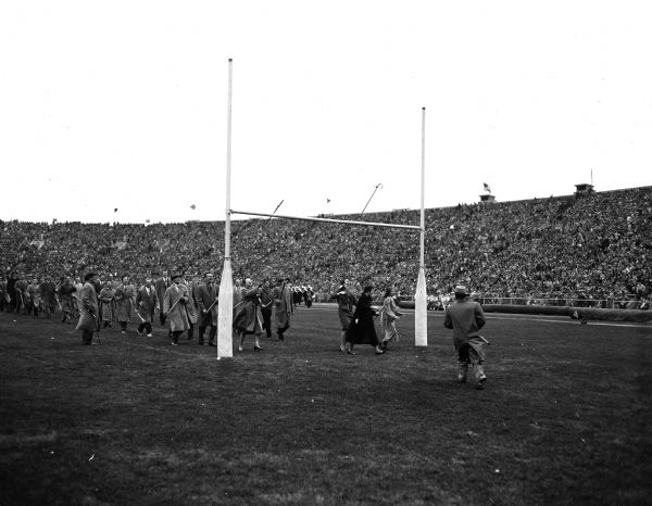 Senior law students throw canes over the goalpost at the University of Wisconsin Homecoming Game against Iowa. Nearly one hundred students, including four women, were led by Professor Ray Brown of the University Law School. Tradition says that if the cane is caught by the student, the student will win his or her first case.