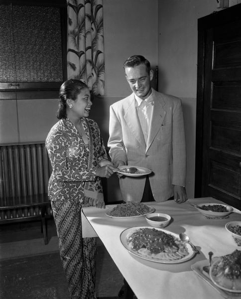 The Luther Memorial Church Young Adult Club hosts an Indonesian meal. Mrs. Yate Iwan, daughter of Secretary of State of Indonesia, is standing beside Richard Langsdorf, Young Adult Club president.