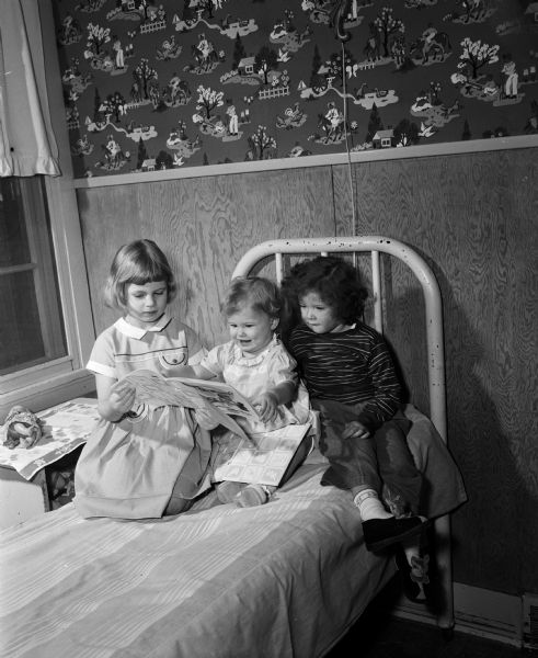 Three children look at a picture book at the Morningside Sanatorium for tuberculosis patients. Money from the sale of Christmas seals was used to redecorate the childrens' rooms.