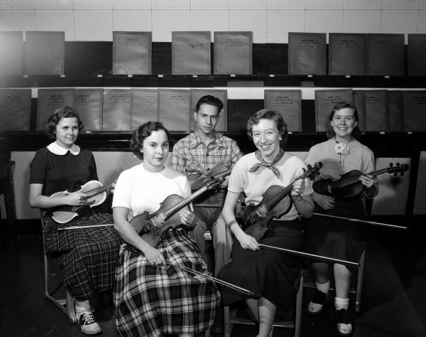 Group portrait of some of the Central High School Orchestra Pop Concert members with violins. From left to right in the front row are: Mary Rowley and Barbara Burke. Second row, left to right are: Sally Bergenske, Pierre Mohos and Nancy Goodrich.