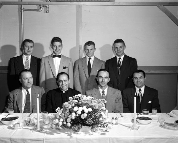 The Waunakee High School championship football team attends a banquet. They are, seated left to right: Principal Robert Riehl, Reverand Wayne Turner, Wisconsin High School Coach Harold Metzen, and Waunakee Coach Dick Trotta. Seated left to right are: Assistant Coach Dave Hash, Ed Hellenbrand, and Tom Raimisch.