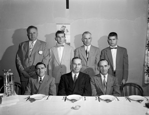 Group portrait of the principal participants at a banquet honoring Sun Prairie's undefeated football team, sponsored by the Lions Club. Seated, left to right: Willard Borchert, George Watson, C.E. Wetmore. Standing, left to right: Joe Bedner, Charles Slattery, Francis Sheehan, Dave Chase.