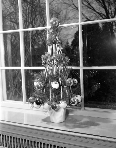 "Umbrella Tree," an original holiday table/window decoration utilizing old umbrella spokes, was created by Ethel (Mrs. Philip H.) Falk of 3721 Council Crest. The displays were sponsored by the West Side Garden Club and shown at the home of Genevieve (Mrs. Walter) Dakin of 4110 Mandan Crescent.