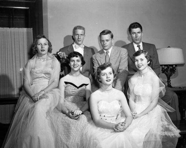 Portrait of seven members of Shriners youth groups in formal dress; the boys were in the De Molay club and the girls were in the Rainbow Girls club.  Some of the members of the Rai-Molay Holiday Dance 'Royalty' are shown. They are, from left, in the front row: Jean Stich, queen of the dance, Barbara Nemetz, Janet Massay, and Joan Massay. Back row: Bill Habich, Tom Howe, and Carl Lindenlaub, king of the dance.