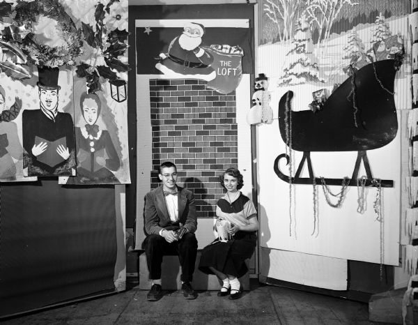 Portrait of Larry Brown, West High School student, and Donna Tupper, East High School, seated by Christmas wall decorations at the Loft, a Madison teen organization.