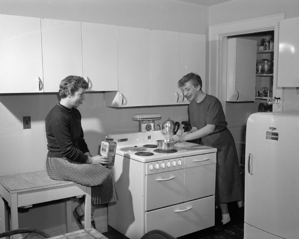 Barbara Schaeffer (left) of Chicago and Catherine LaBerge of Ladysmith cook their own meals at the Ellsworth House, a residence for UW coeds. The house was located at 422 North Murray Street.