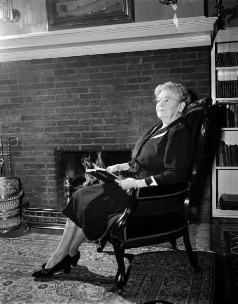 Ada Moseley of 616 North Carroll Street demonstrates a Christmas custom by sitting near a fireplace reading "A Christmas Carol" by Charles Dickens.