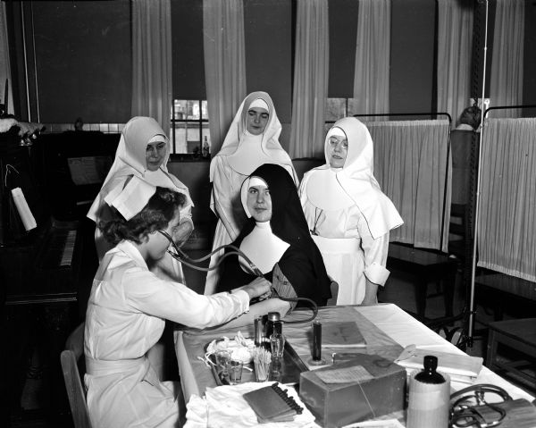 Four St. Mary's hospital nuns participate in the hospital staff blood drive. Red Cross nurse Barbara Zimmerman takes the blood pressure of Sister Mary Virgine. Waiting their turn are, left to right: Sister Mary LeoRita, Sister Kenneth Marie and Sister Mary Hilaire.