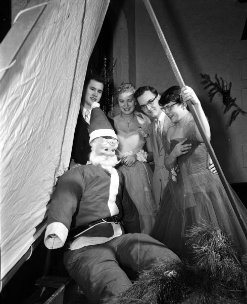 Four youth admire a large Santa Claus doll at the University Club's dance for high school and college-age children of club members. From left, they are: William Roark, Rita Wittich, William Bunce and Marjorie Napper.