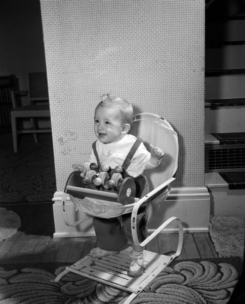 Mark Evon Henry sitting in a bouncy seat. The photograph was one of a series featuring the children born one year ago on New Year's Day of 1953.