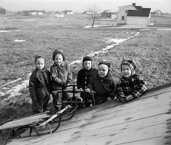 Several neighborhood children are standing by a toboggan slide set up by the Orchard Ridge Community Club. From left, they are Polly Buchholtz, Debbie Woodington, Jimmy Morse, Louis Buchholtz, and Jimmy Young.