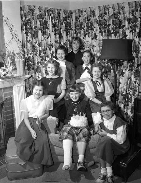 Group portrait of guests at Marilyn Reuhl's eleventh birthday party, after she broke her leg in an ice skating accident. Guests positioned in an inverted V are:  Patty Parent, Virginia Reuhl, Marcia Richgels, Jean Parker, Sandra Brown, Patricia Radder, and Joelyn Ripp.
