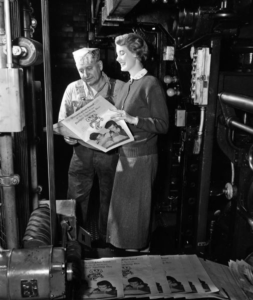 Nancy Staudenraus, State Journal librarian and assistant Spelling Bee director, looks over 1954 Spelling Bee pamphlets as they come off the press. Ernest P. Green, day foreman of the pressroom, stands beside her.
