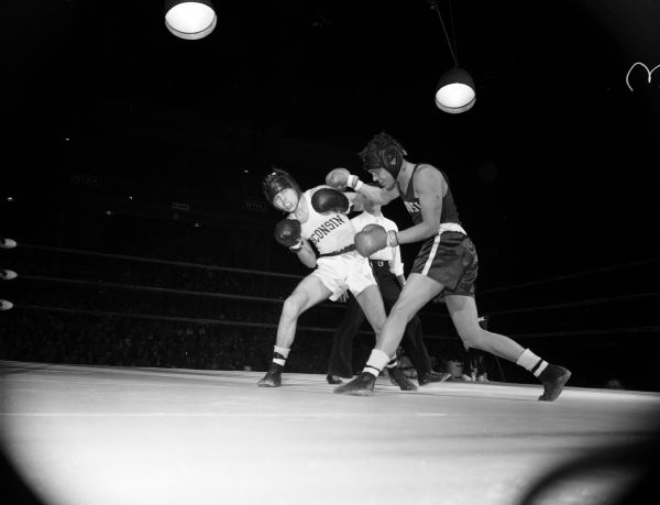 Jerry Hursh of Madison (right) throws a right that lands on the shoulder of Bill Judson, Chicago, in the third round of their match during the University of Wisconsin Boxing Tournament of Contenders.