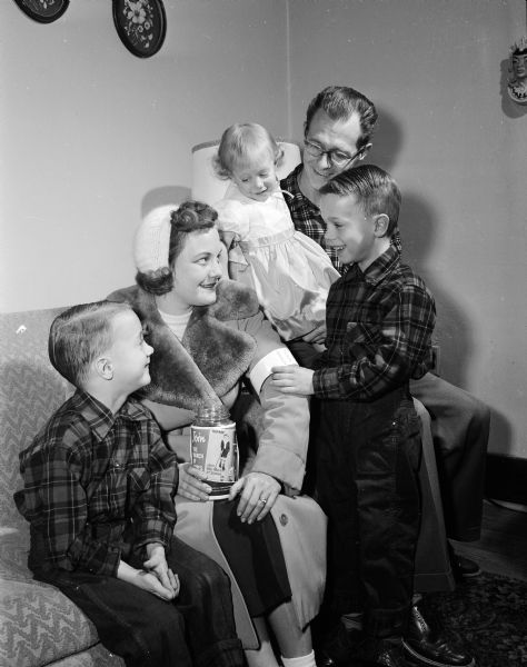 Portrait of Mr. and Mrs. Ronald Brown and their three children. Russell, right, is still fighting the effects of his paralysis from polio; he pins a Mothers' March band to the sleeve of his mother's coat. Mrs. Brown will be participating in the march, a fund raiser for March of Dimes. The other children are Randy, 6, and Deborah, 2.