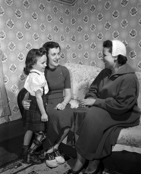 Portrait of five-year-old Lynn Stenrud with her mother Mrs. Ingvald Stenrud (middle), and Mrs. Robert Huehel (right), all from Deerfield. Lynn is wearing a brace on her right leg as a result of having polio. The women will be participating in the upcoming Mothers March for March of Dimes.