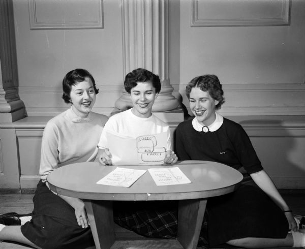 As part of Co-ed's Week, an event designed to combine features of special interest to college women, three University of Wisconsin women look over a copy of the "Co-eds Job Market" published by the Associated Women Students organization. Left to right: Kathleen Daubert, Chicago; Annetta Scheers, Milwaukee and Nancy Schneiders, Madison.