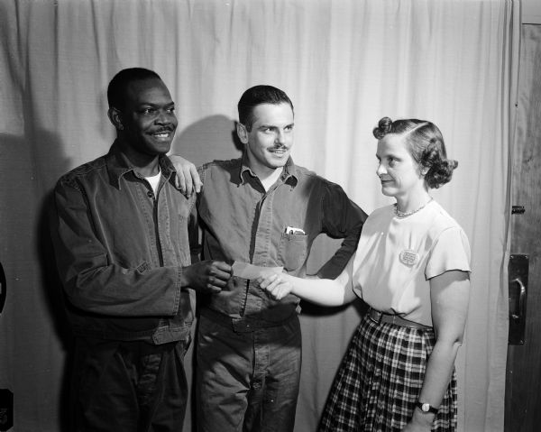 Luida Sanders (right), a "writer's aide" and  a state public health educator, presents first and second prizes to two writers and patients at the Madison Veterns Administration hospital. Anson Mount of Waukesha (center) is resting his arm on the shoulder of Eugene Lane (left) of Chicago. Both men are sporting zip jackets and moustaches.