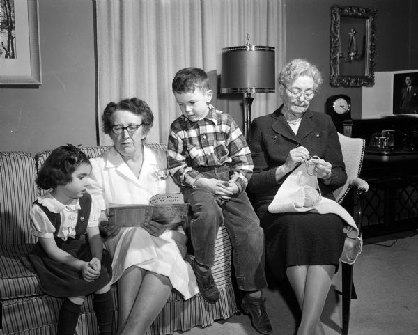 Mrs. Frank J. Vaughn reads to 6-year-old Kenneth Lemmer, Jr. and 5-year-old Ann Lemmer while the children's grandmother, Kath B. Morrissey, works on an afghan. Mrs. Vaughn received child care employment through the Woman's Service Exchange.