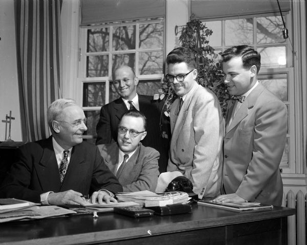 Rev. James R. Love (left), chaplain at Mendota State Hospital for the Mentally Ill, sits at a desk beside four ministers receiving twelve weeks of clinical training. The others are Owen Akers, seated, and, standing, Dwight Townsen, Arthur Tees, and Kenneth Smith. The ministers served the patients and learned about mental illness, its diagnosis and treatment.