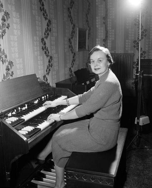 Portrait of Luan Hoesly seated at an electric organ keyboard. She and her mother Marion Hoesly, who played a piano, performed duets for a weekly radio broadcast on WIBA and WIBA-FM. For more than five years, they recorded their show in their living room. The recordings were broadcast as their weekly radio show.
