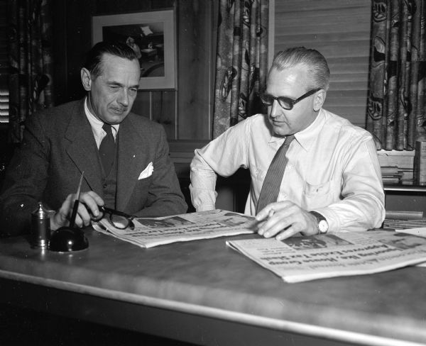 Roy L. Matson, Editor and Don Anderson, Publisher, seated at a desk looking over issues of the Wisconsin State Journal