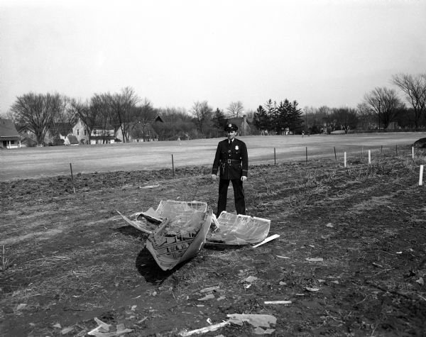 Police Officer Robert Ferris stands near a canopy that ripped loose from a Truax Field jet fighter and landed in the Rentschler Floral Company plat a block from Madison West High School.