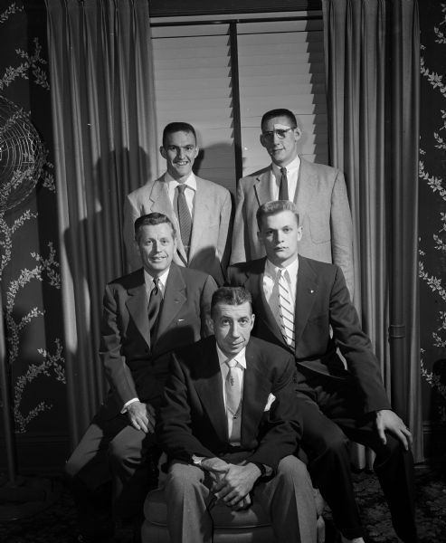 Group portrait of University of Wisconsin coaches and players honored at a banquet at the close of the season. Seated, left to right, are: Fritz Wegner, assistant varsity and head freshman coach; Harold E. (Bud) Foster, head varsity coach; and Richard Zeiger, freshman captain from Milwaukee Rufus King high school. Standing are: Bob Weber (left), from Lodi, honorary captain; and Paul Morrow, most valuable player.