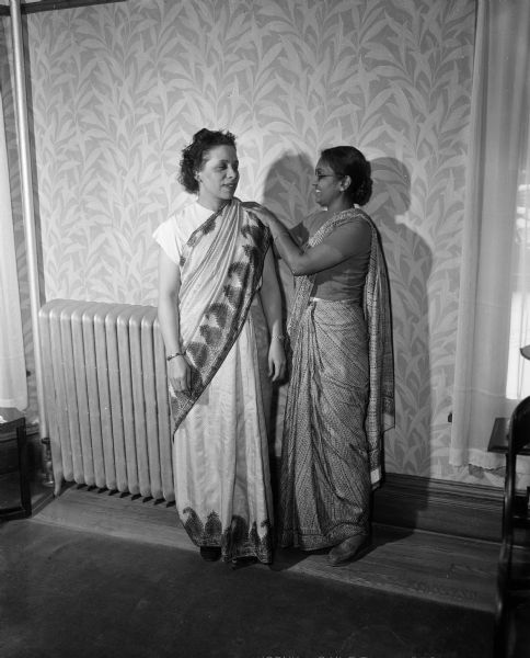 Anna Chandapillal (right) pleats the shoulder drape of the sari modeled by Lenore Gourdin (left).